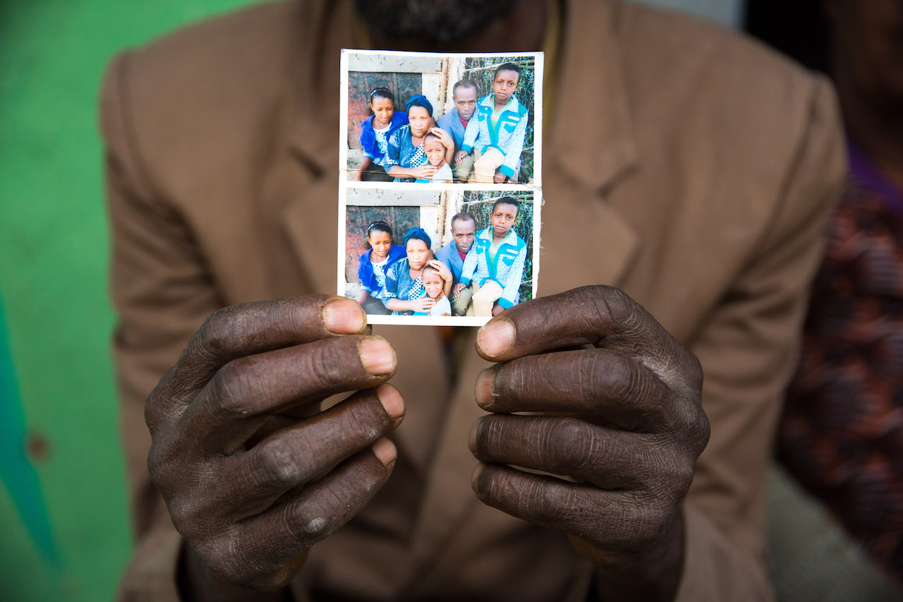 noen hender som viser frem fysiske bilde av en familie